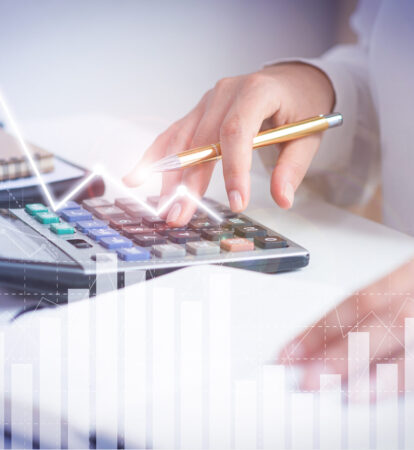 Accountant calculating profit with financial analysis graphs. Notebook, glasses and calculator lying on desk. Accountancy concept. Cropped view.